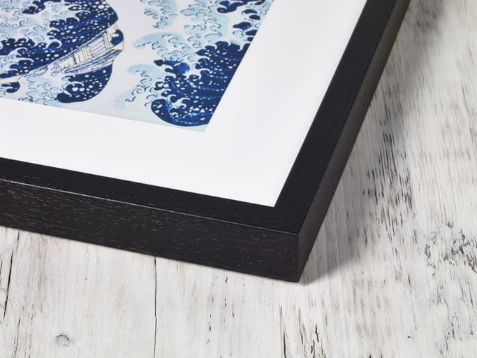 A corner of a high quality framed image made from wood painted black